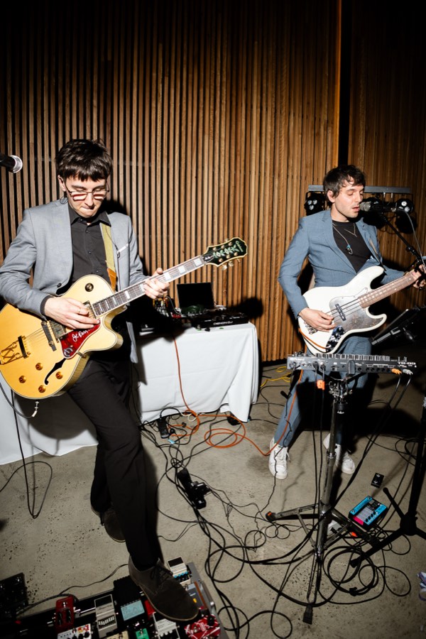 Lemonade Fuzz playing live: one member on hollow-body guitar, the other on bass, with pedalboards and cabling across the floor.